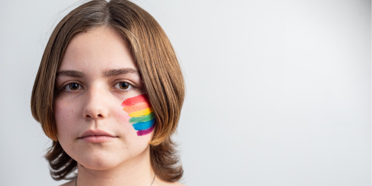 lgbtq teen with pride flag painted on cheek