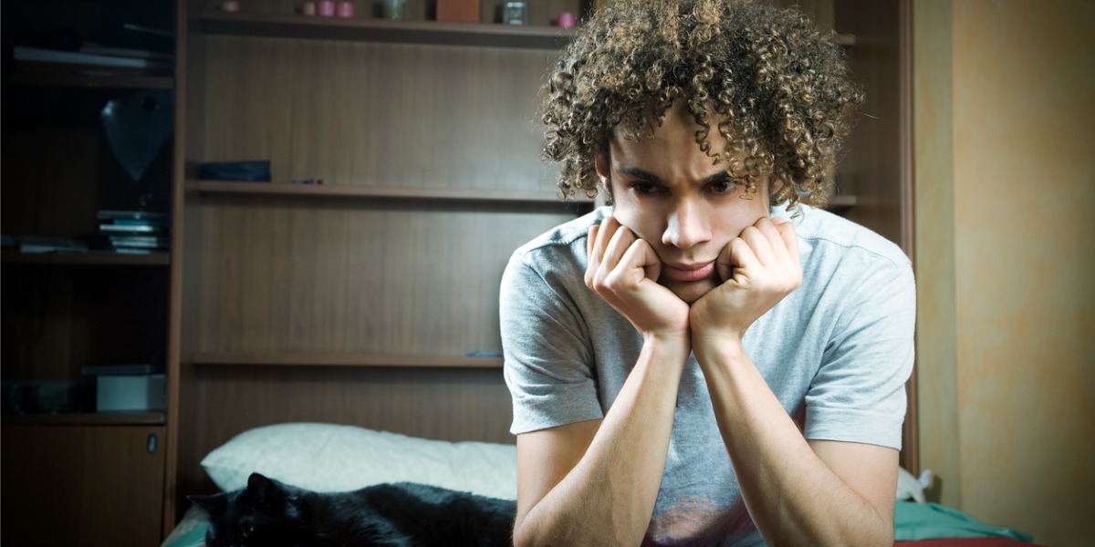 depressed teen boy sitting with head in hands