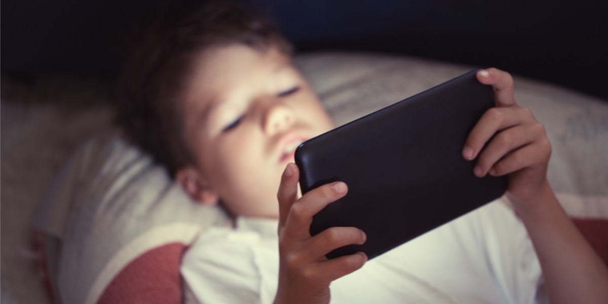 young boy watching tablet screen at night