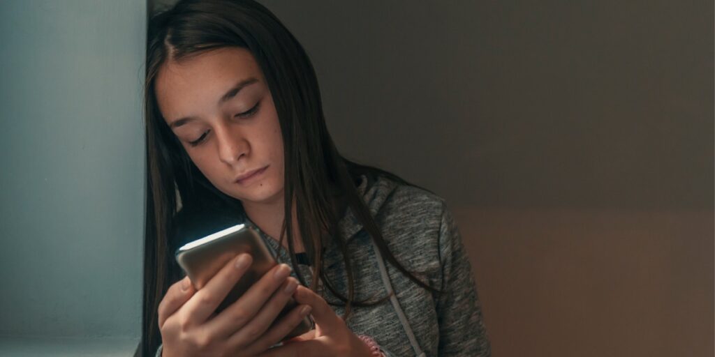 teen girl looks distressed viewing social media on phone