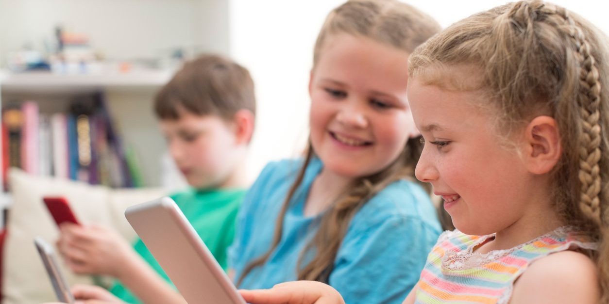 children looking at their devices to show screentime