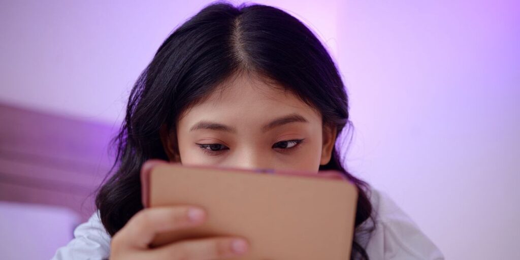young woman staring at her tablet screen and doomscrolling