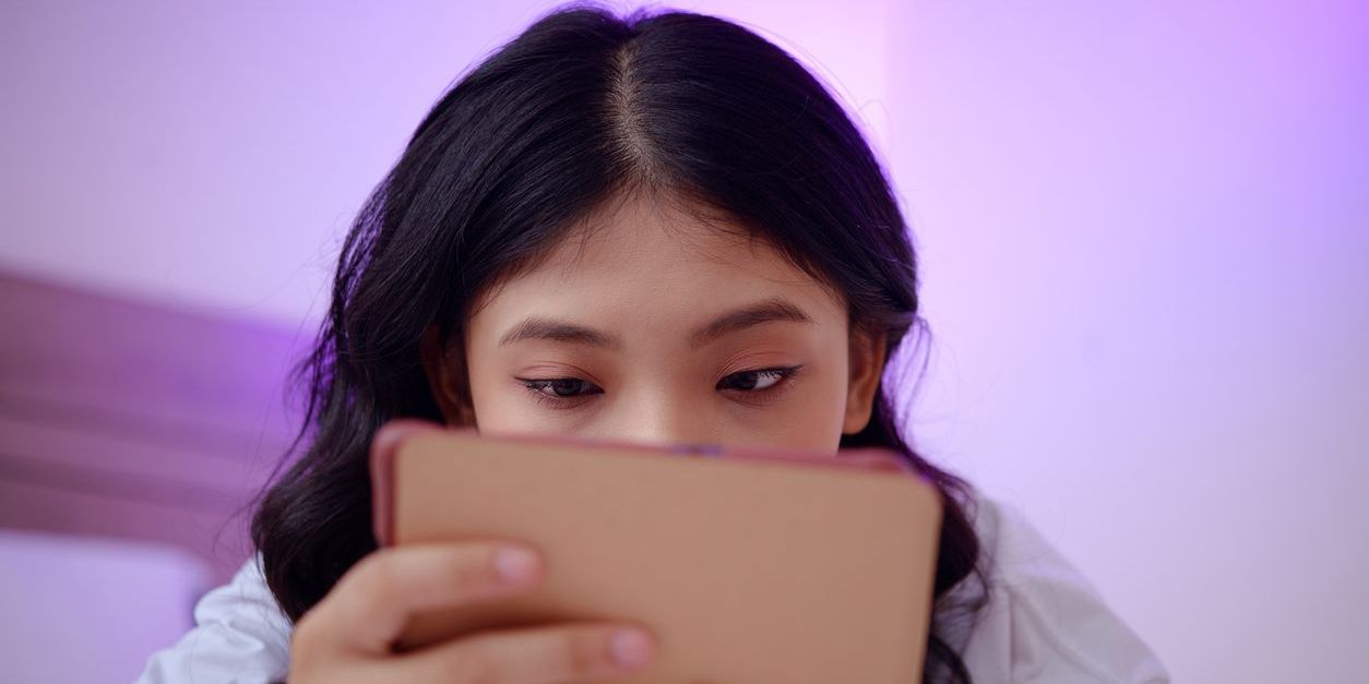 young woman staring at her tablet screen and doomscrolling