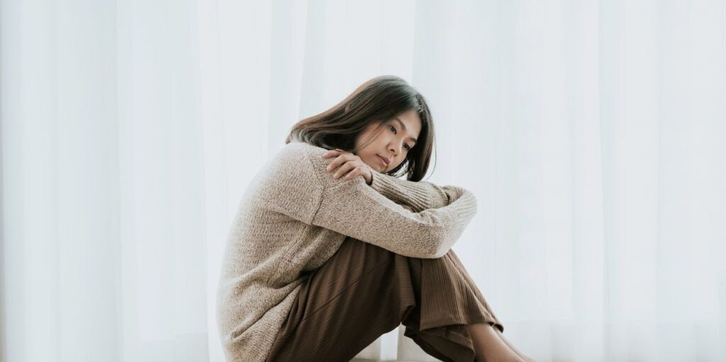 young asian woman sitting as if depressed