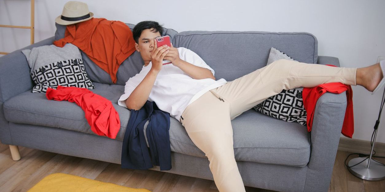 young man on couch looking at social media on phone